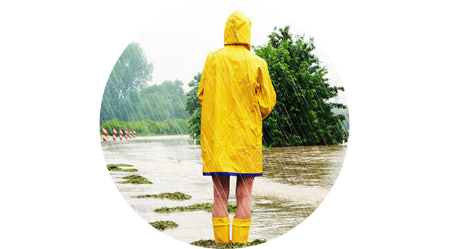 In Regenkleidung steht ein Mensch im Hochwasser